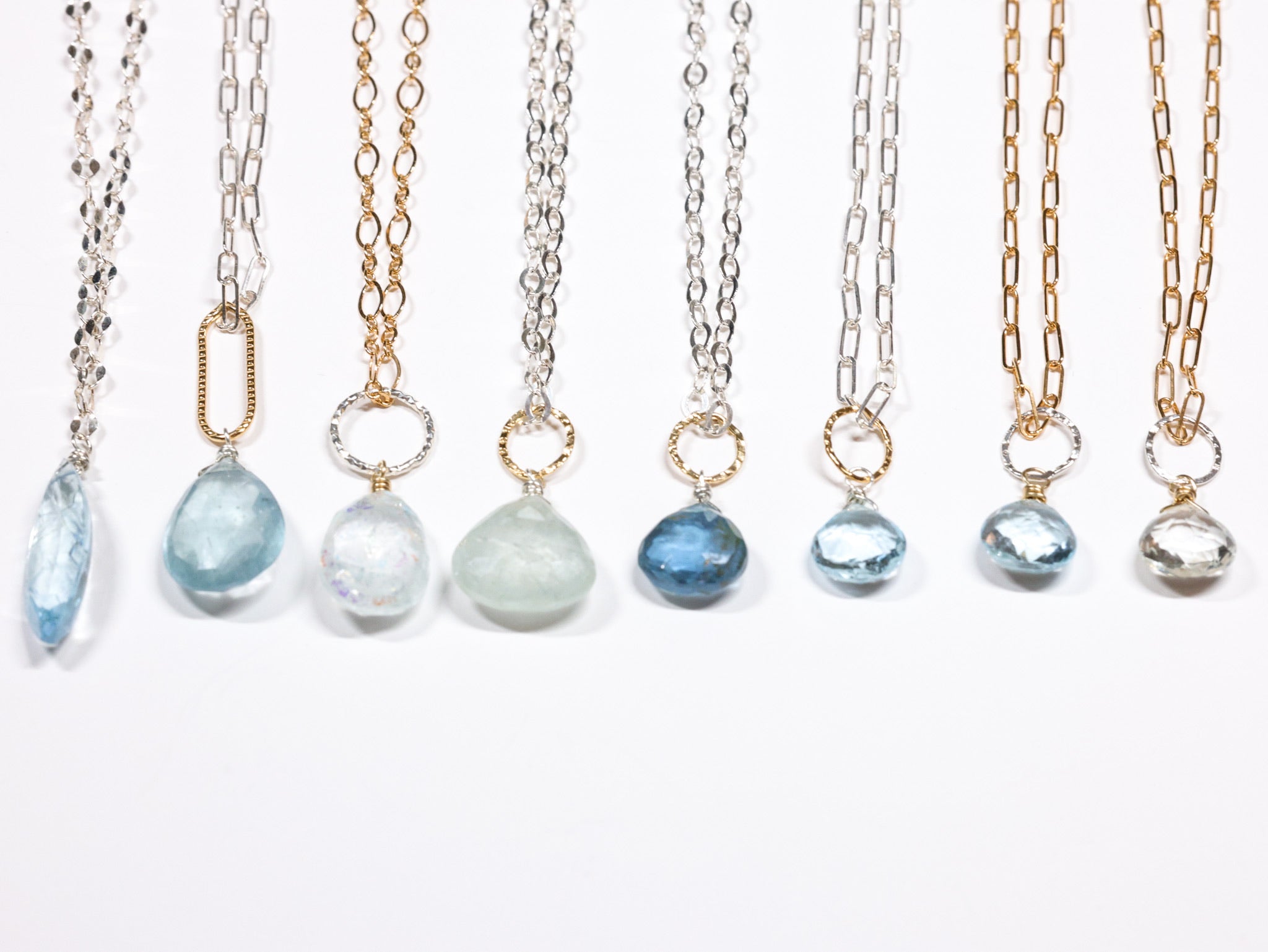Assorted gemstone pendant necklaces with aquamarine, quartz, and silver or gold chains by Nina Halls