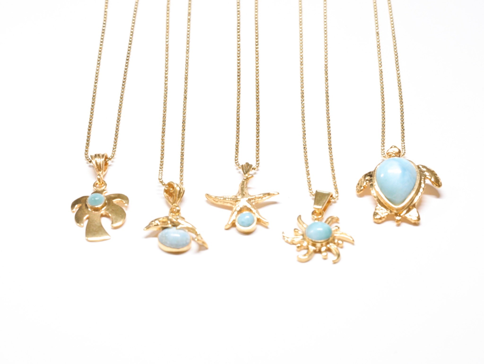 Gold pendant necklaces with turquoise stones in palm tree, dolphin, starfish, sun, and sea turtle designs from Ardor Boutique
