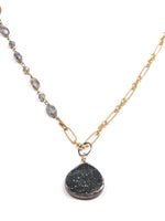 Close-up of a handmade necklace featuring labradorite beading on one side, gold-filled chain on the other, and a teardrop black druzy pendant.