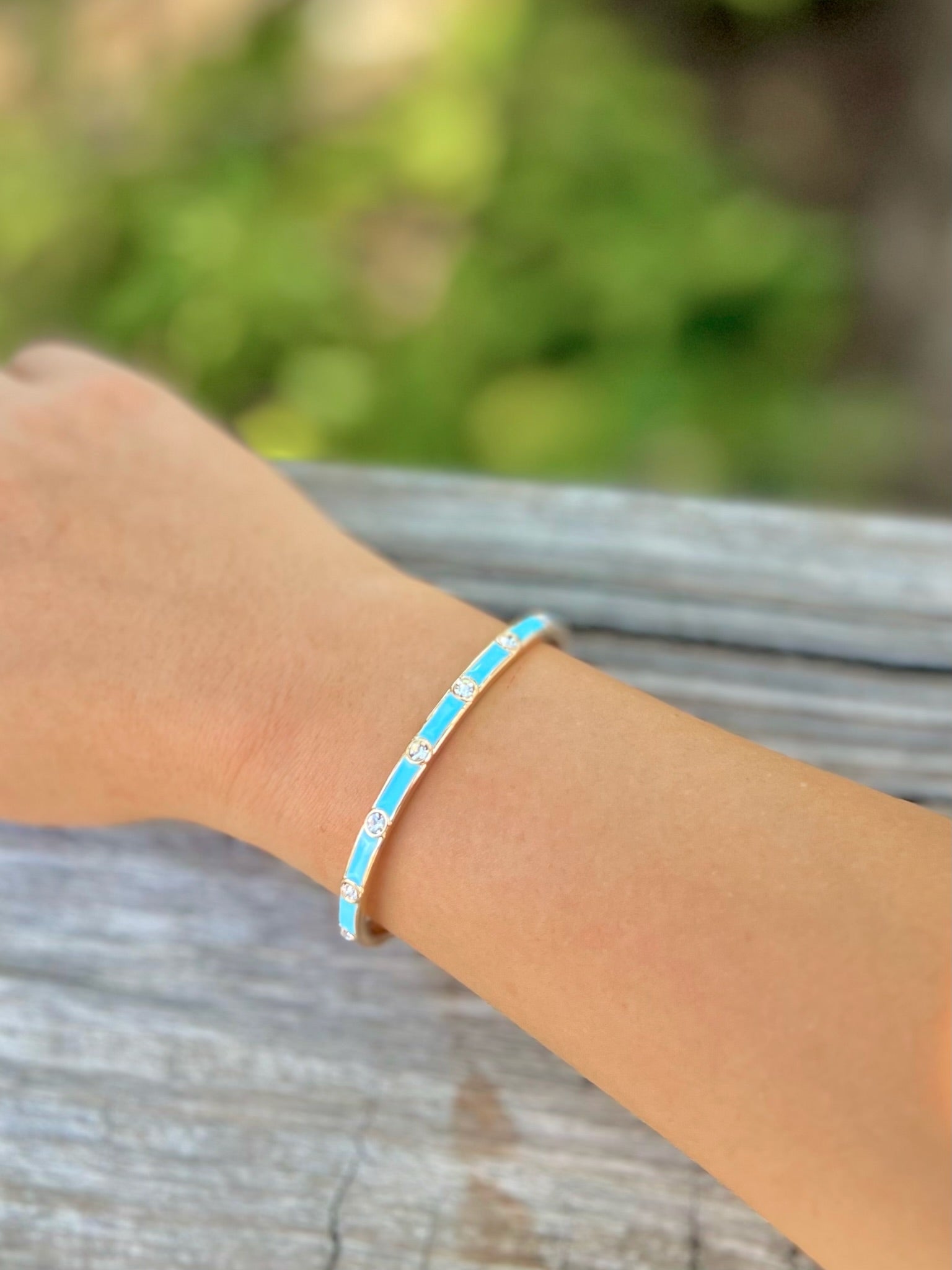 Turquoise and gold crystal cuff bracelet worn on wrist.