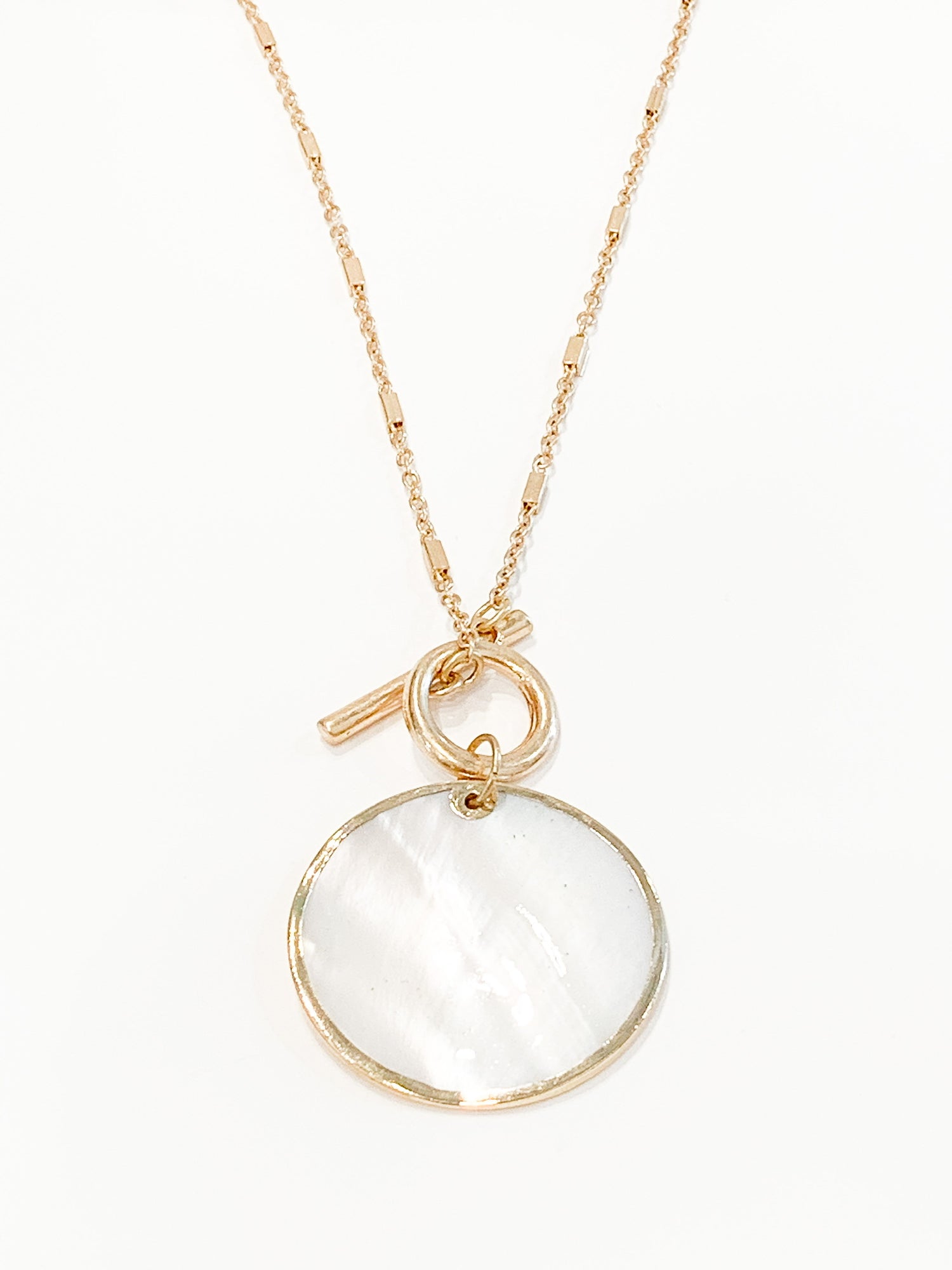 Gold necklace with a round white pendant on a white background