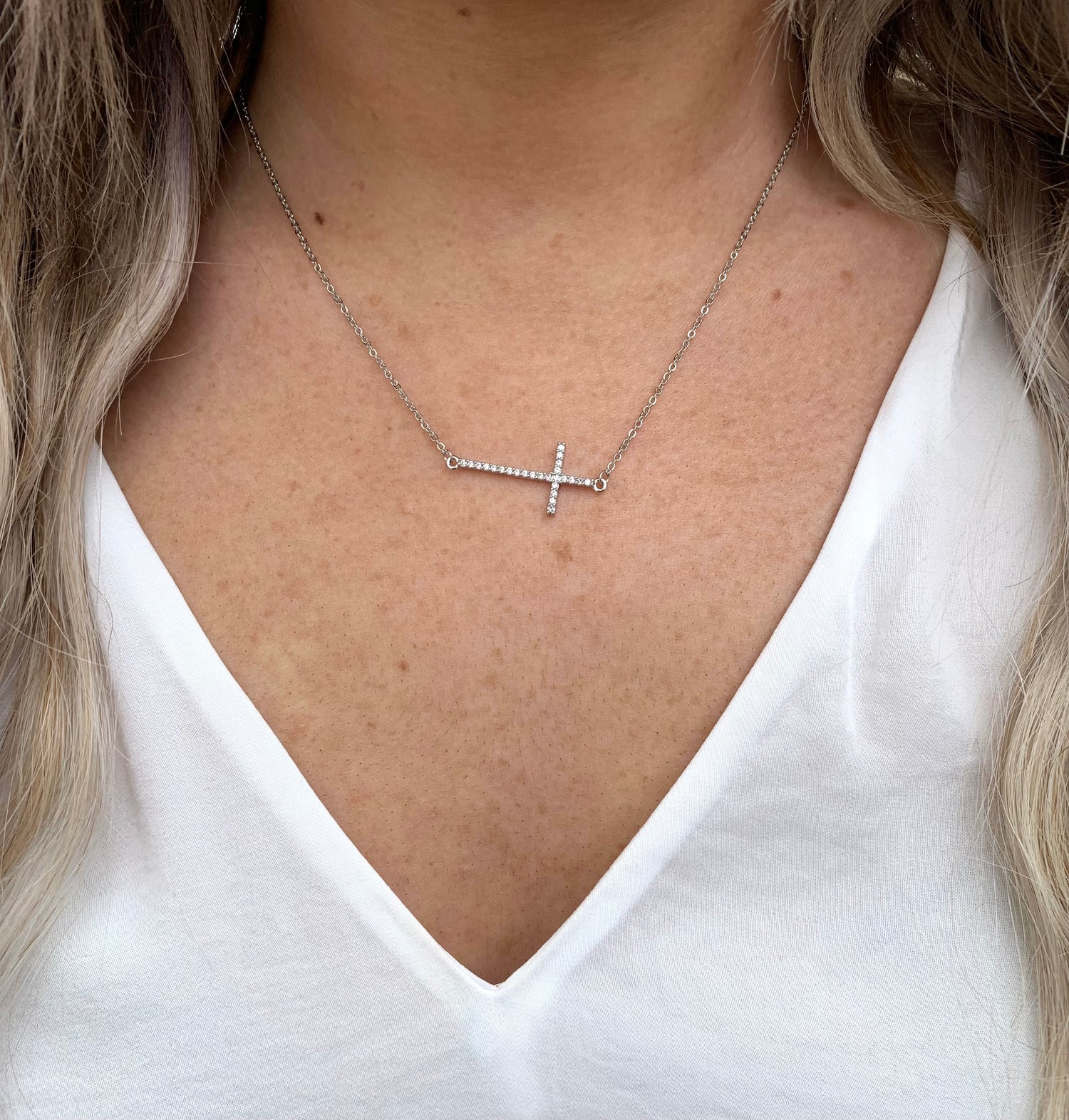 Silver sideways cross necklace on model.