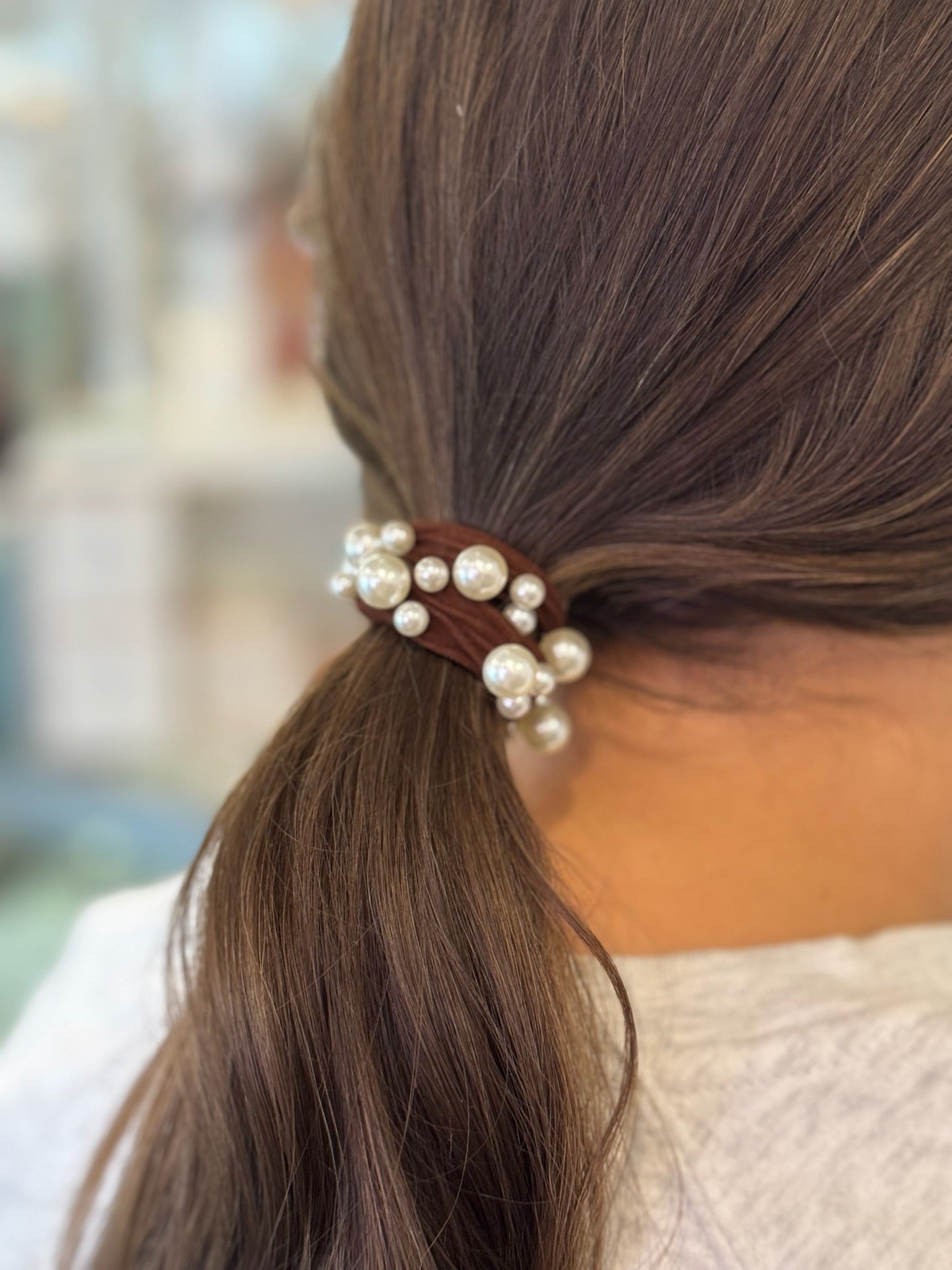 Hair tie with pearls in a ponytail against a blurred background