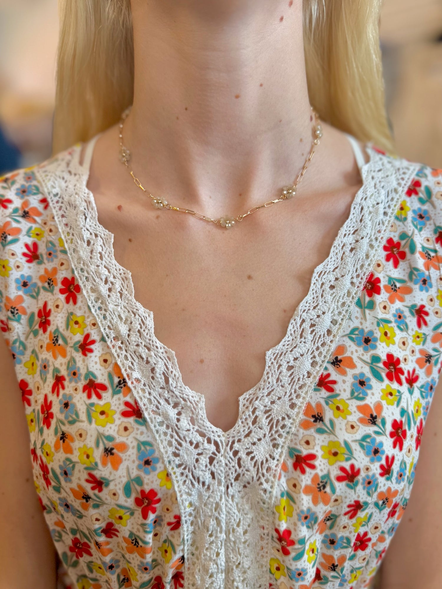 Daisy Floral Necklace in beige with gold-tone chain and beaded clusters on models neck