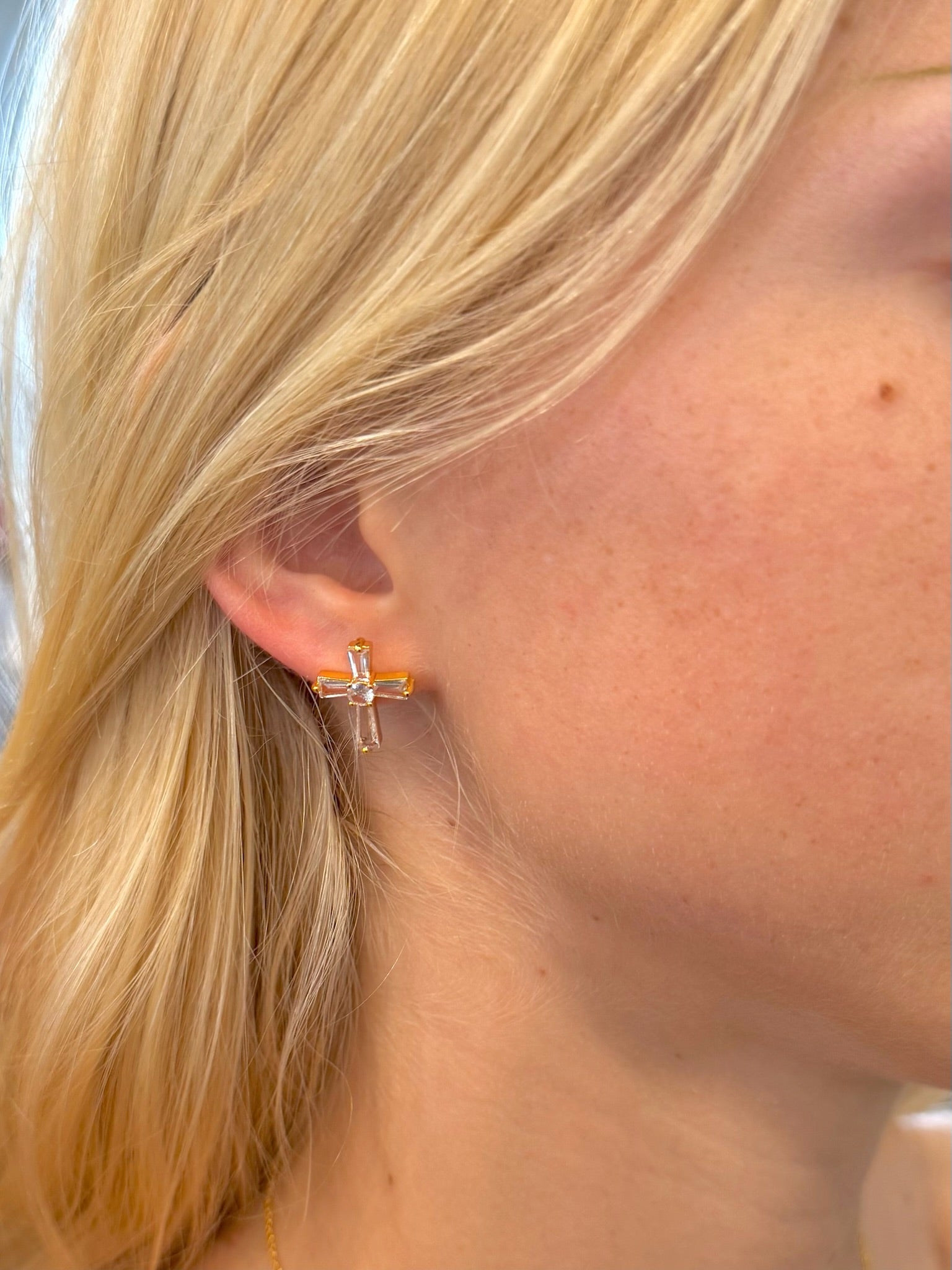 Grace Cross Studs in gold with baguette-style crystals on woman's ear