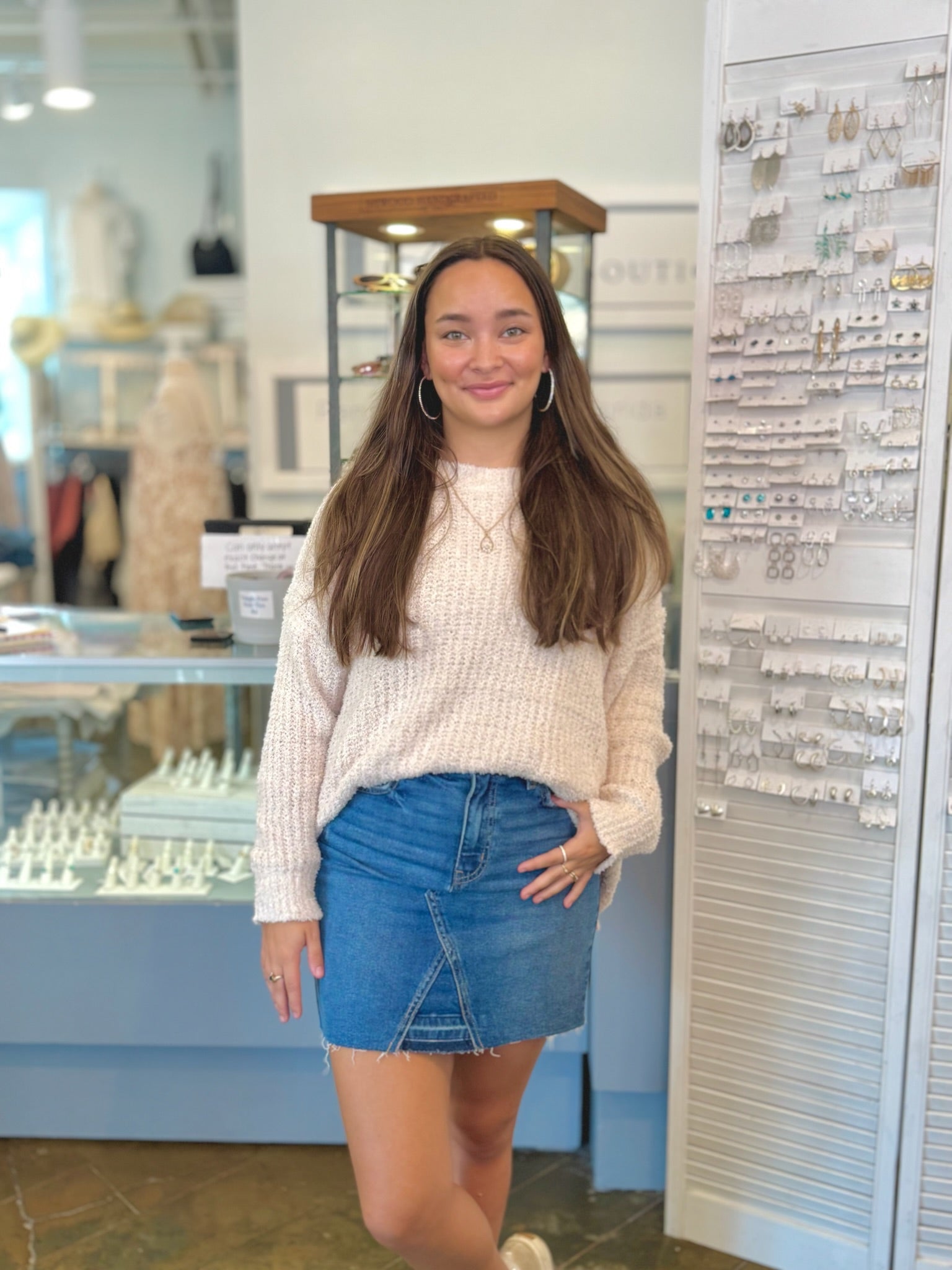 Woman standing in a store with jewelry displays in the background