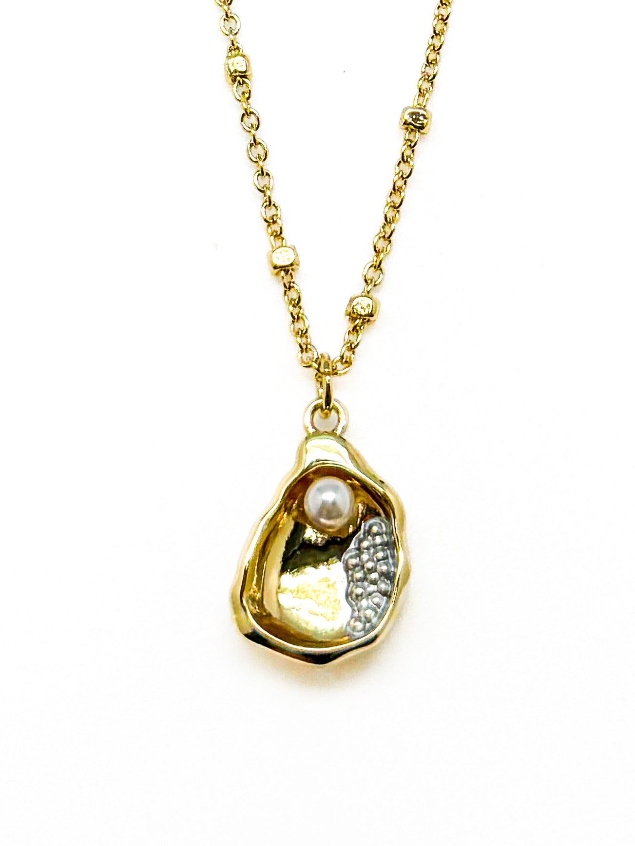 Gold necklace with a pendant featuring a pearl in a golden oyster