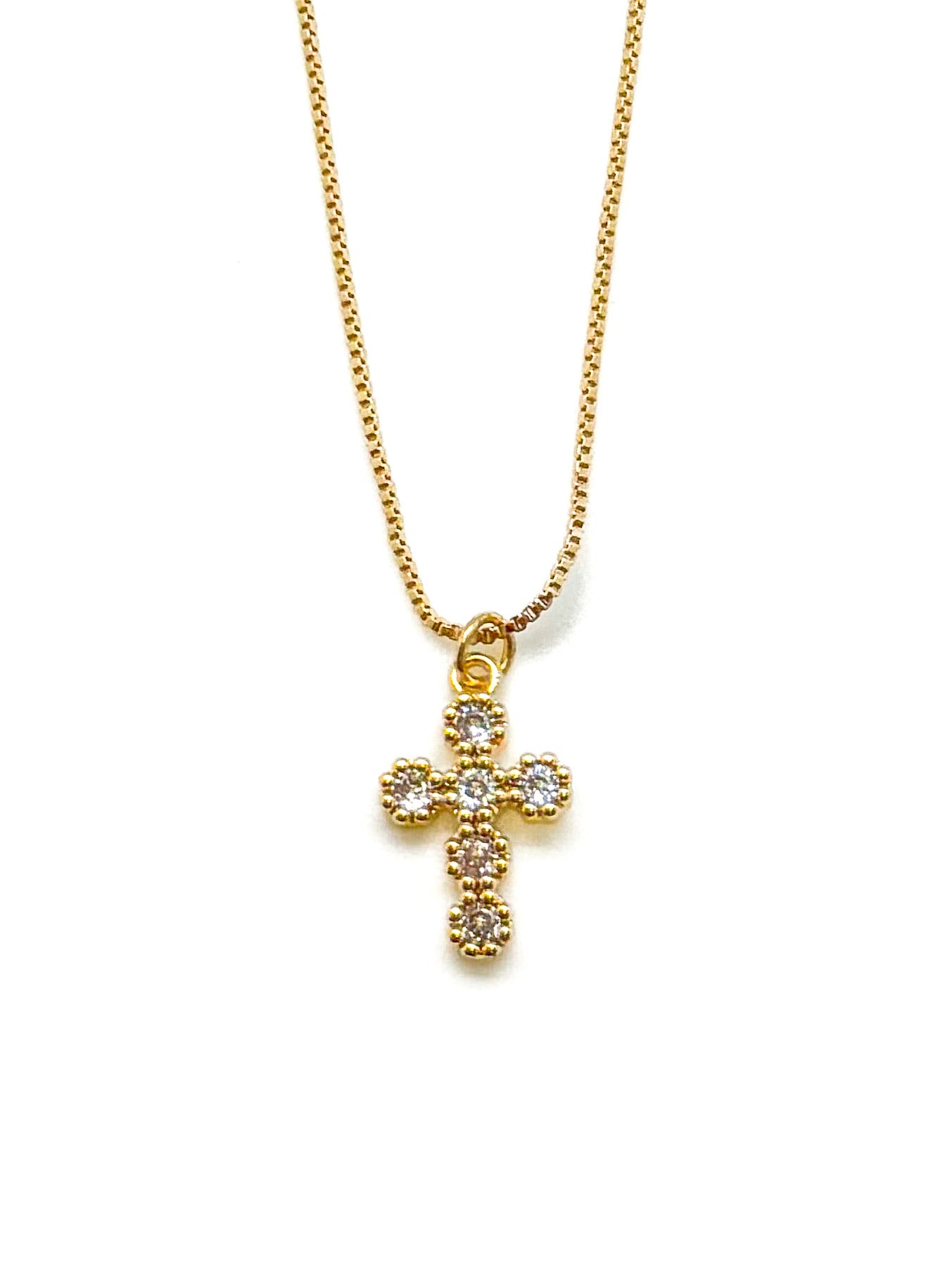 Gold cross necklace with clear stones on a white background