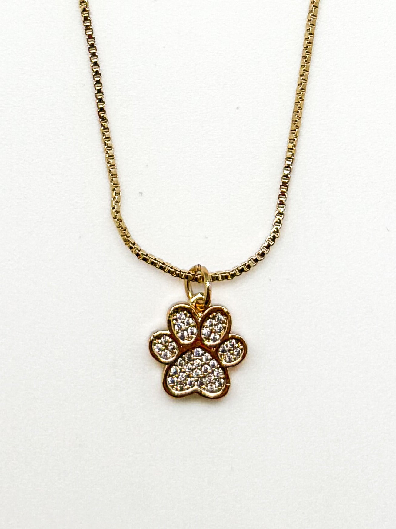Gold necklace with a paw-shaped pendant on a white background