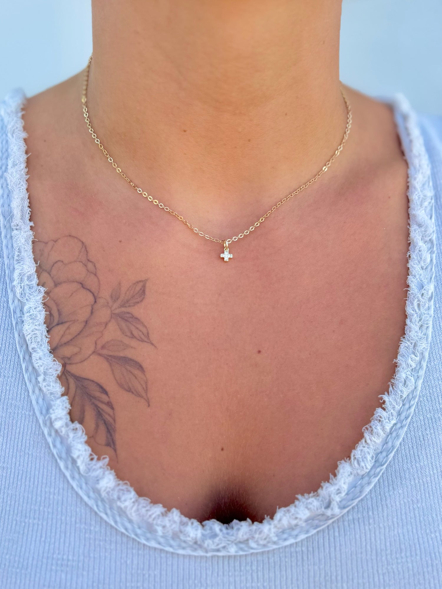 Adjustable 15–17.375" Aveline Mini Cross Necklace in gold-filled chain with delicate cross charm being worn