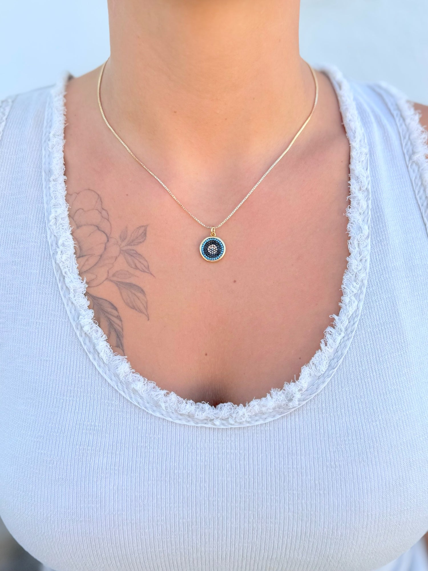 Necklace with a circular pendant featuring colorful stones being worn