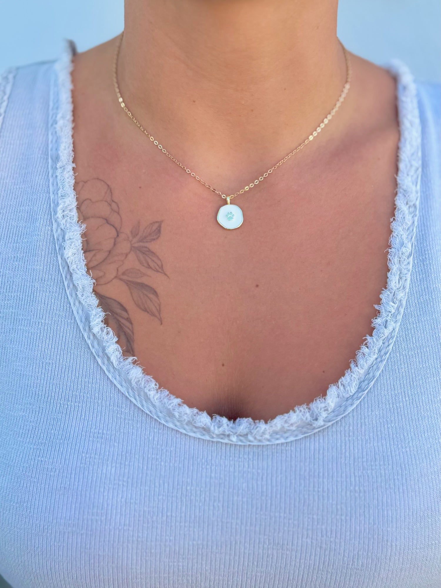 Necklace with a pendant worn by a person against a light blue background