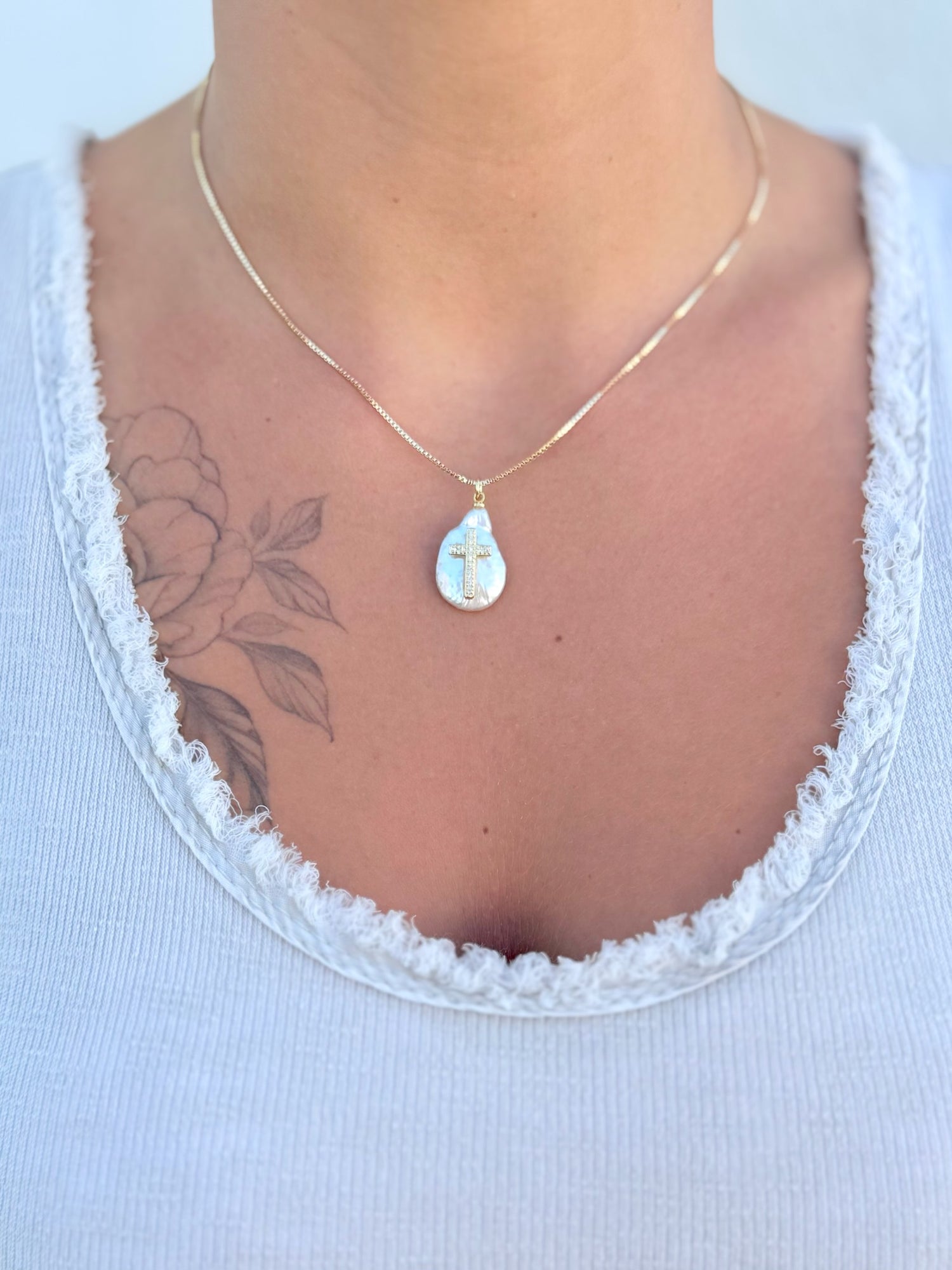 Adjustable 16–18" 18k gold-filled chain with freshwater pearl cross pendant, worn by a person.