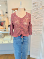 red crochet top on a mannequin with blue jeans in a store setting