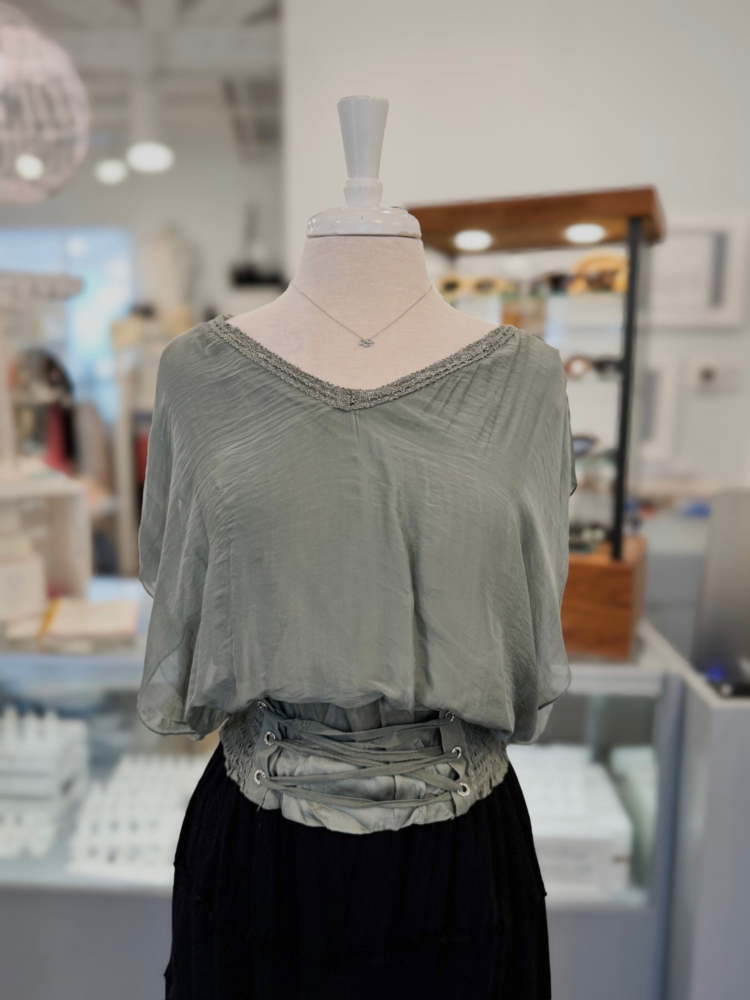 Green blouse on a mannequin in a store setting