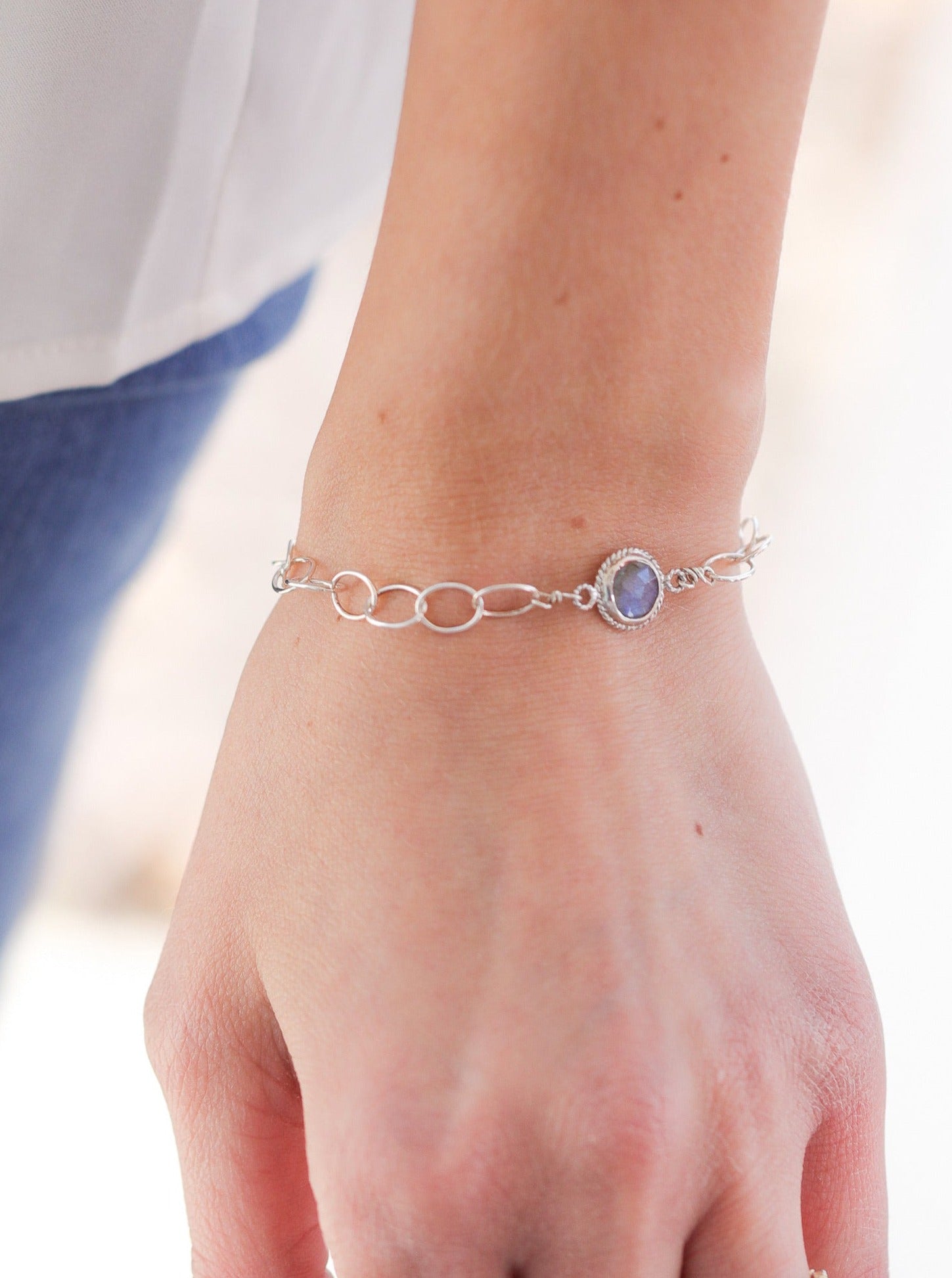 Athena Bracelet on wrist Nina Halls jewelry Labradorite Blue Collection Labradorite center stone Nickel-Free Sterling Silver Lobster Clasp Adjustable length to fit the smallest to larger wrists. Length options: shorter to mid, mid, and longest Beautifully handcrafted with love and care Expect slight variations in each piece due to the one of a kind nature of the gemstones. Each piece comes in a small Nina Halls leatherette pouch and gift box Found exclusively at Ardor Boutique