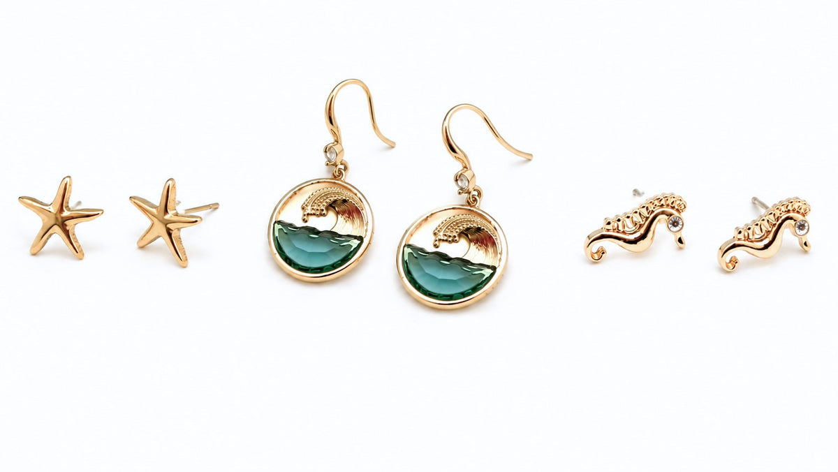 Three pairs of ocean-inspired earrings featuring gold starfish studs, teal ocean wave dangle earrings, and gold seahorse studs on a white background for the Sea Life Earrings collection at Ardor Boutique.