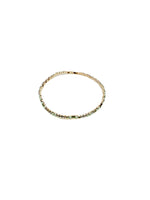 Gold bracelet with green gemstones on a white background