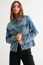 Medium wash denim jacket with button front, chest flap pockets, side pockets and classic collar at Ardor Boutique.