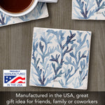 Square ceramic coasters with a blue coral branch pattern on a white background, arranged on a gray wood surface with a cup of coffee partially visible at the top left. A 'Proudly Manufactured in the USA' badge and promotional text appear at the bottom.