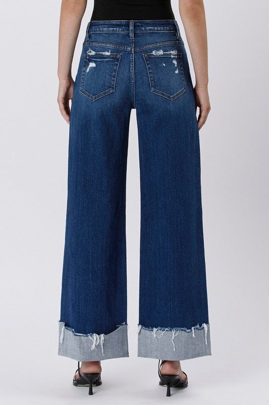 Blue wide-leg jeans worn by a person on a white background