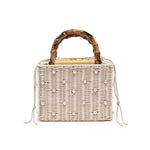 Wicker handbag with bamboo handle and pearl embellishments on a white background