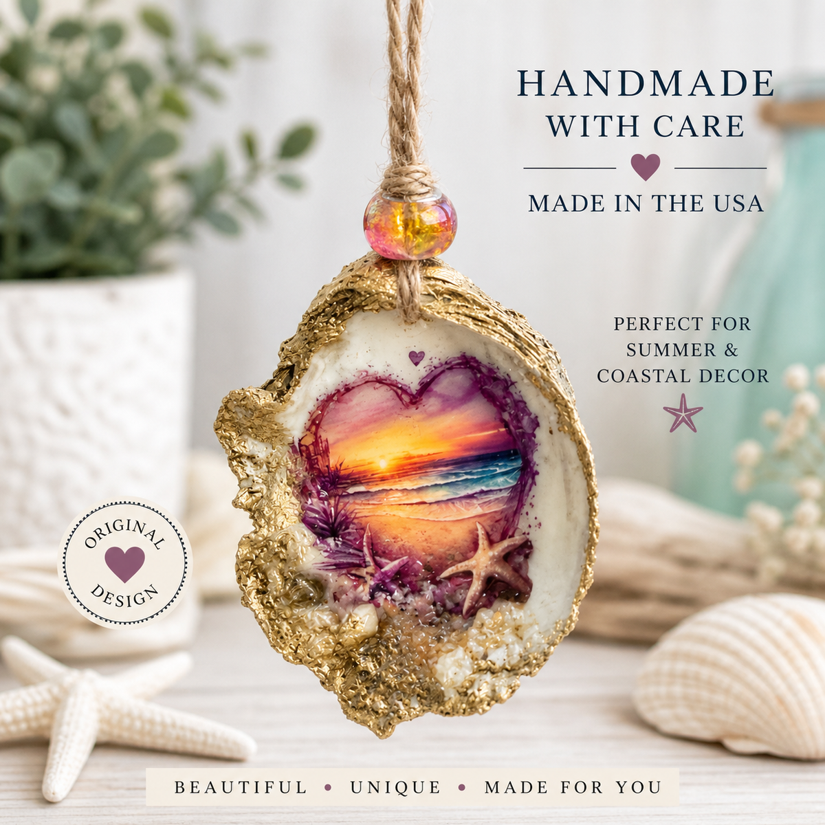 A handmade oyster shell hanging ornament with a gold glittery edge, a purple and orange sunset heart design in the center, and a small pink bead at the top. The ornament is displayed on a light wooden surface with seashells, a potted plant, and decorative text overlays.