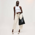 Woman holding a black handbag against a white background