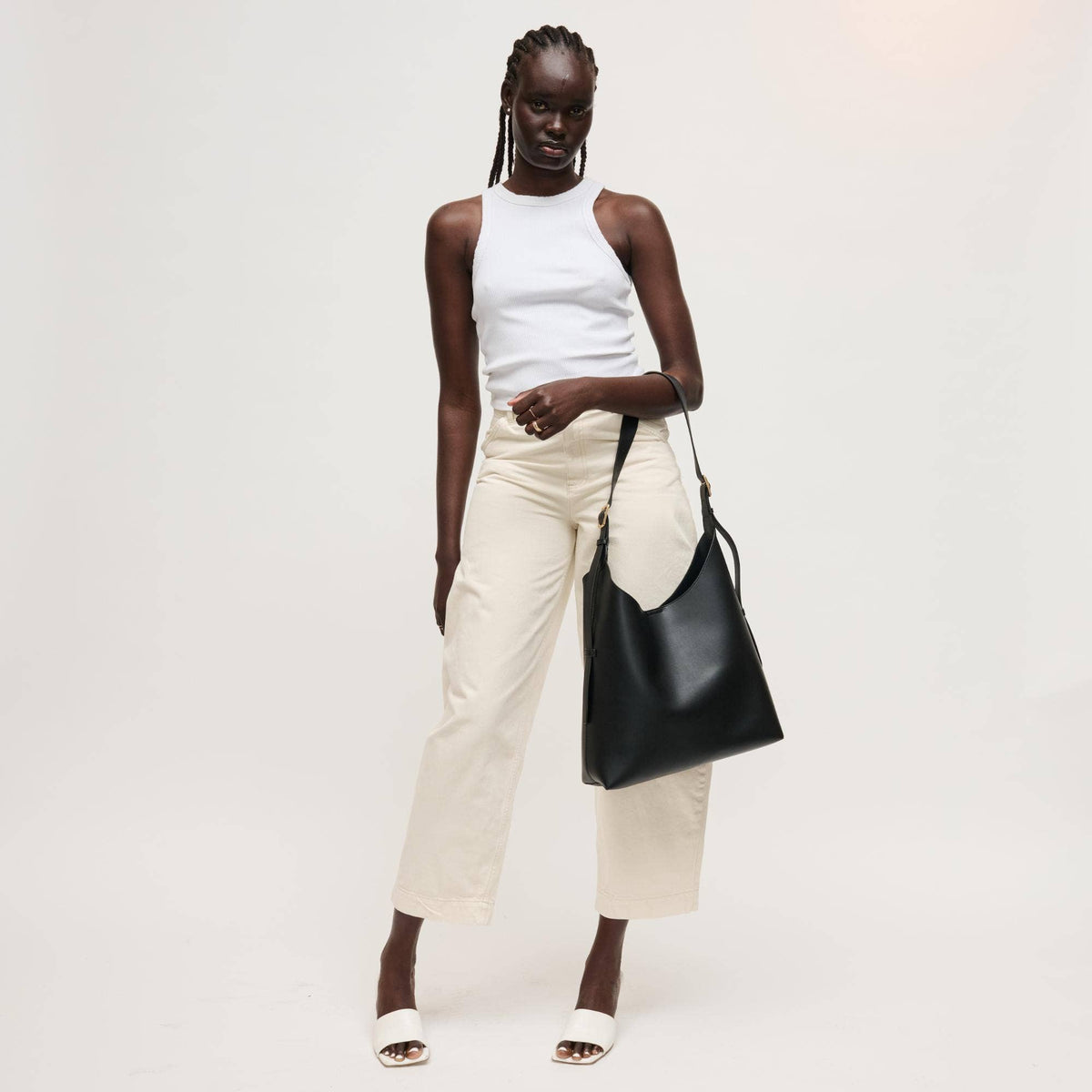 Woman holding a black handbag against a white background