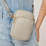 A light Grey crossbody bag with gold-tone hardware, worn crossbody over light-wash denim overalls.