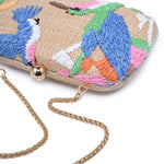 Colorful woven clutch with embroidered parrot design and gold chain strap on a white background