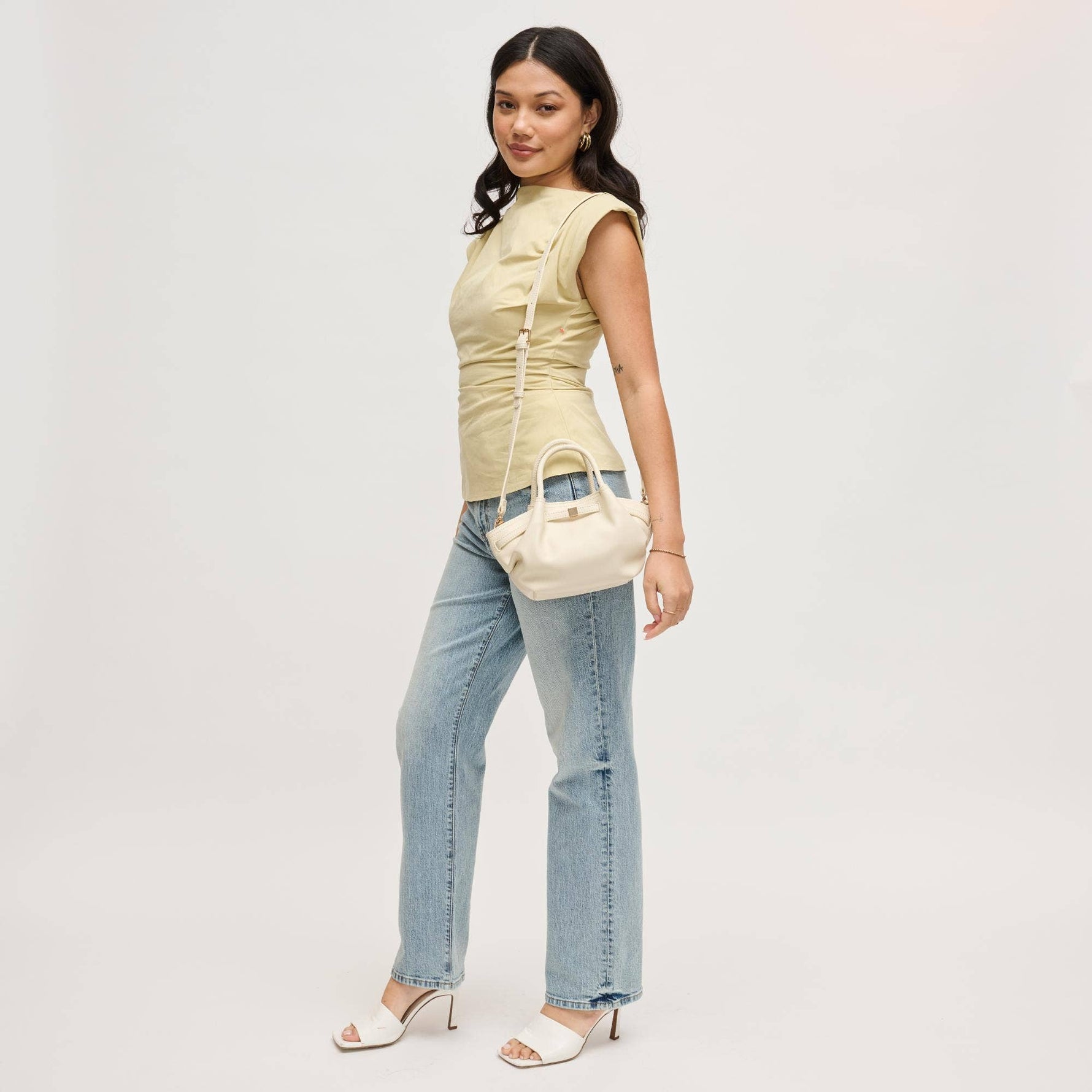 Model wearing the Selena Crossbody in cream with the adjustable shoulder strap, showcasing the soft-structured silhouette and versatile everyday design.