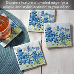 Coasters with blue flower design on a wooden surface with a glass of iced tea.
