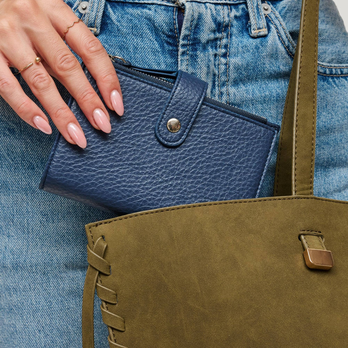 Blue leather wallet held by a hand against a denim background