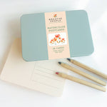Breathe People watercolor postcards in a tin with a pen on a white background