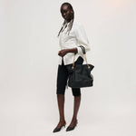 Woman holding a black handbag against a white background