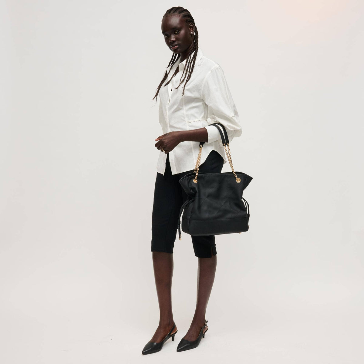 Woman holding a black handbag against a white background