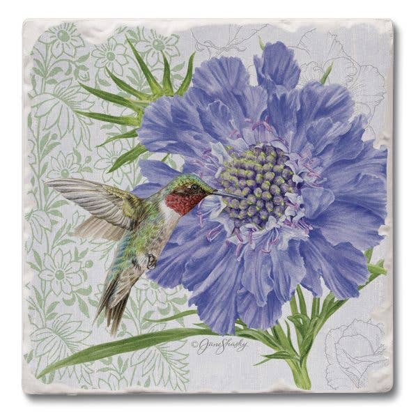 A square decorative tile or coaster featuring a painted floral design with a large blue-purple flower, green leaves, and a hummingbird on a light background with faint floral outlines.