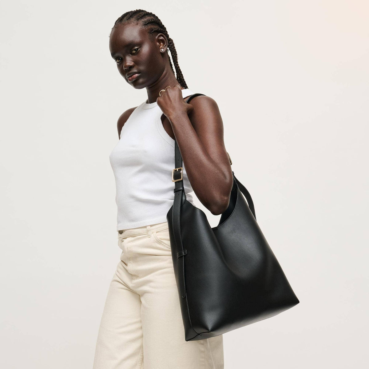 Woman holding a black leather handbag against a plain background