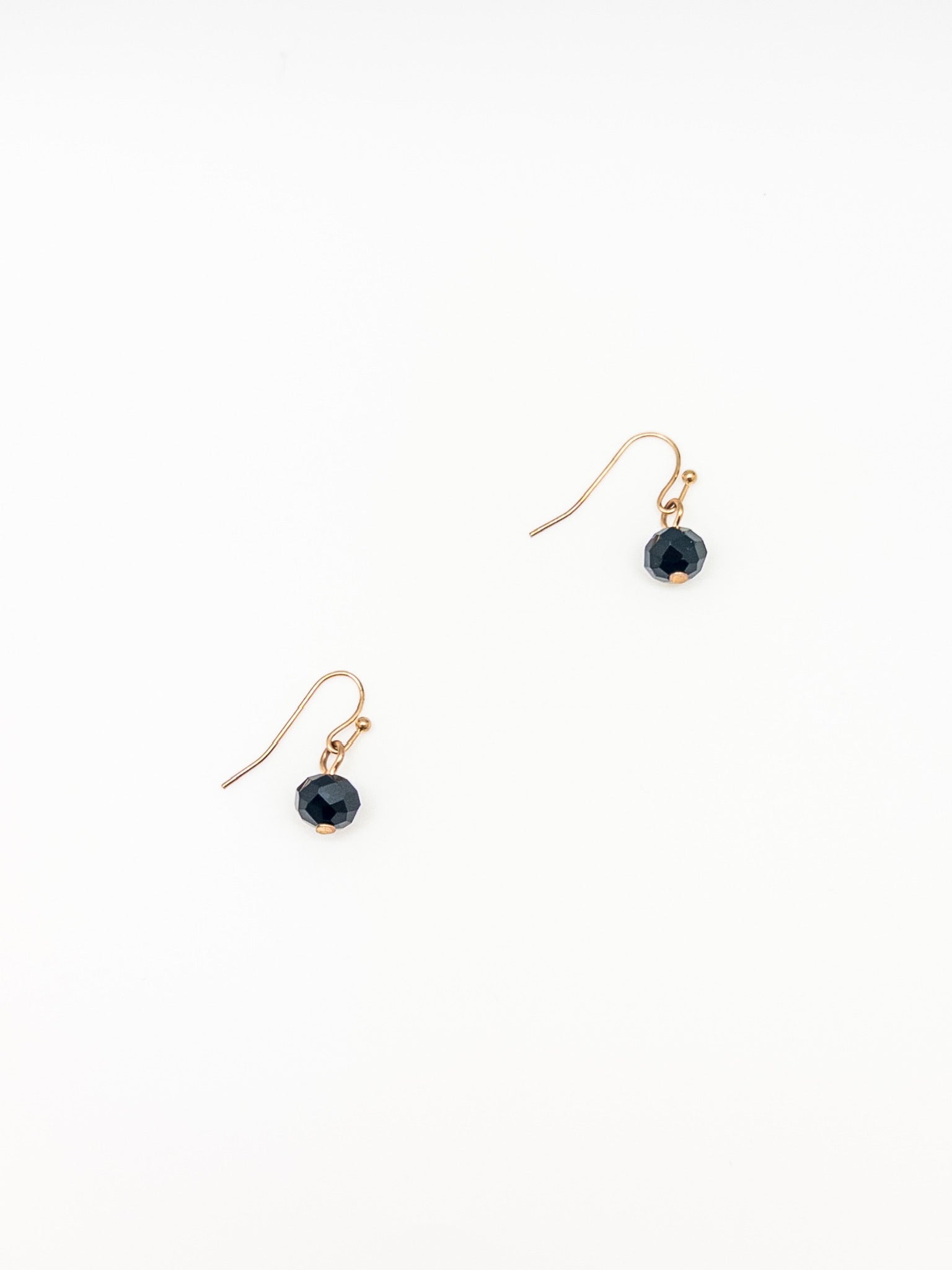 Pair of gold earrings with black beads on a white background