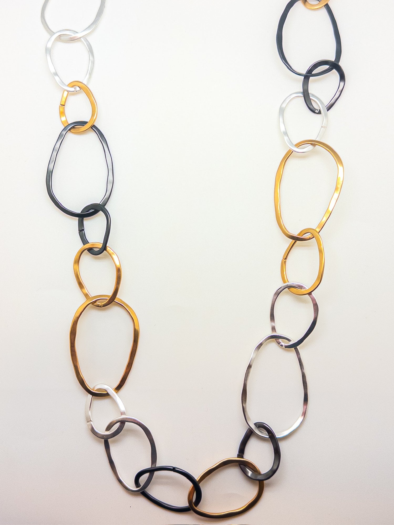 Long 45-inch mixed-metal link necklace featuring organic gold, silver, and black sculpted links.