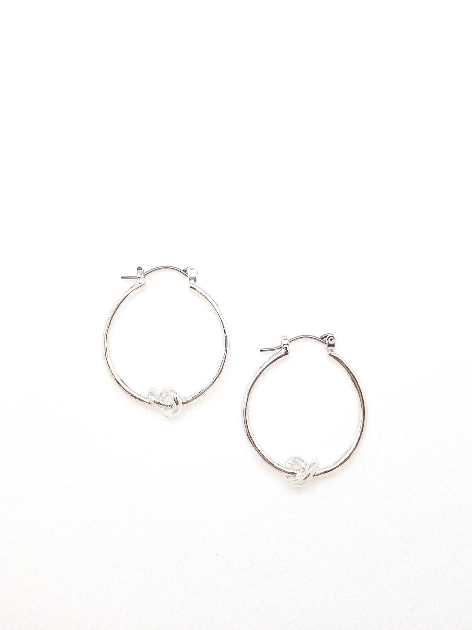 Silver Kelly hoop earrings with a knot detail in the bottom center of earring