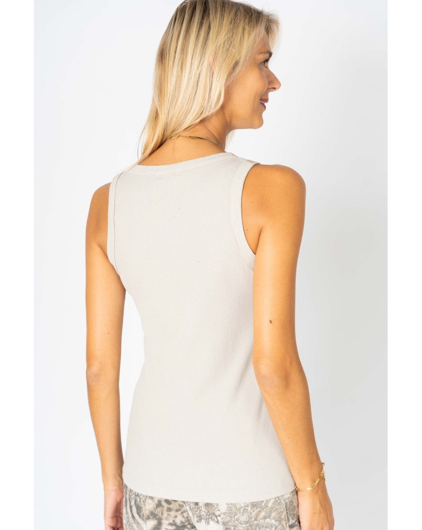 Woman wearing a white sleeveless top against a plain background