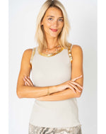 Woman wearing a light-colored sleeveless top with decorative elements on a white background
