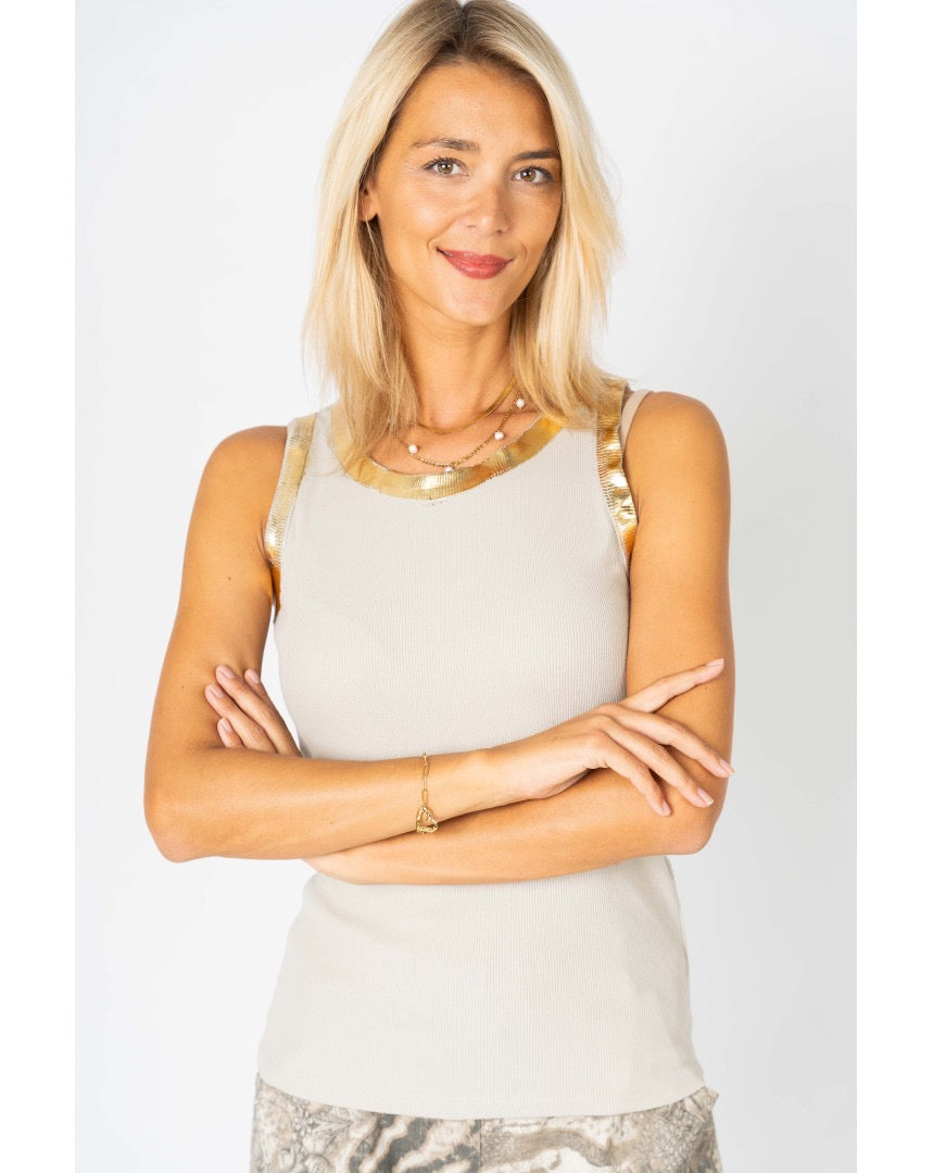 Woman wearing a light-colored sleeveless top with decorative elements on a white background