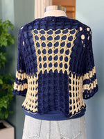 Navy and beige crochet cardigan on a mannequin against a neutral background