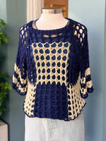 Navy and beige crochet top on a mannequin against a light blue wall.