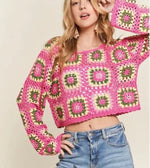Woman wearing a hot pink open knit cropped floral sweater with jeans