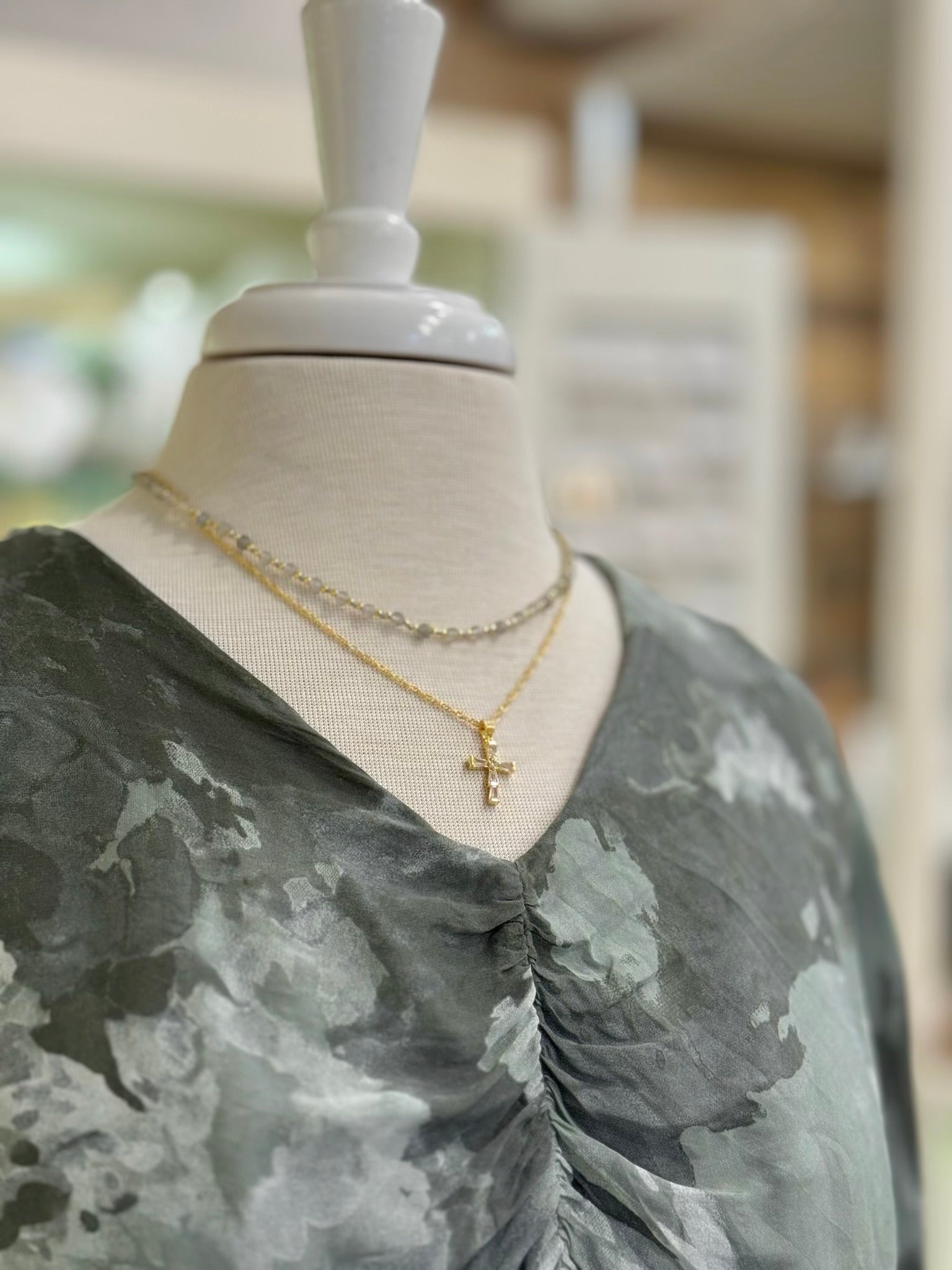 V-neckline and ruched front detail of the Ariella Silk Dress in Olive styled with gold necklaces at Ardor Boutique.