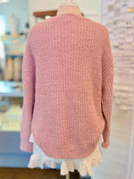 Back view of a mannequin wearing a pink sweater and white ruffle skirt in a store setting